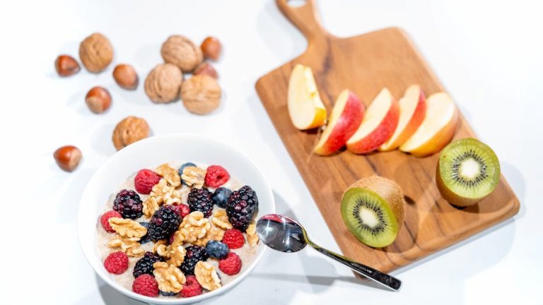 A nutritious breakfast bowl featuring fresh berries and walnuts, served with sliced fruit and kiwi.